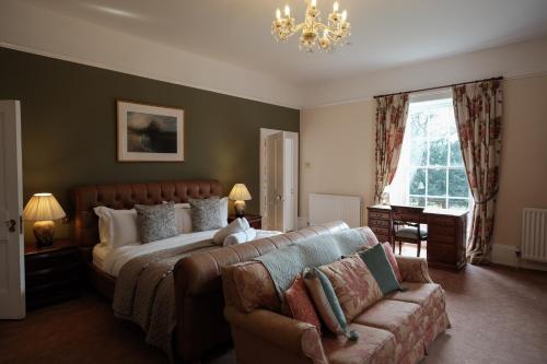 a bedroom with a bed and a couch and a chandelier at Burnhopeside Hall in Lanchester