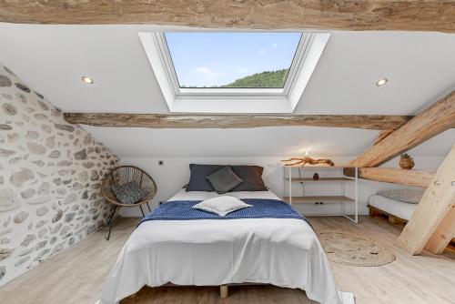 a attic bedroom with a bed and a window at Les Gîtes Du Saro in Chabestan
