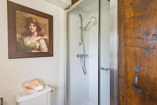 a bathroom with a shower and a painting of a woman at Lanes End by Keepers Cottages in Woodchurch