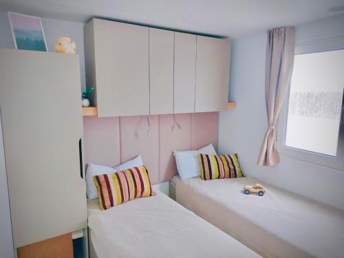 a small room with two beds and a window at Mobile Home Camp Dalmata Orebić in Orebić