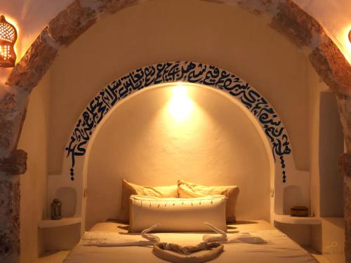 a bed in a room with an arch above it at TenasBook Houch Yassmine in Erriadh