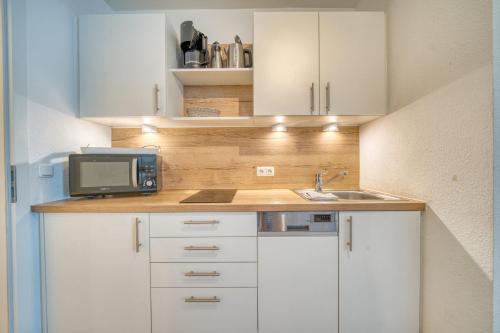 a small kitchen with white cabinets and a microwave at Ferienpark - Haus H, App 0H1107 - Apartment Baltic Panorama in Heiligenhafen
