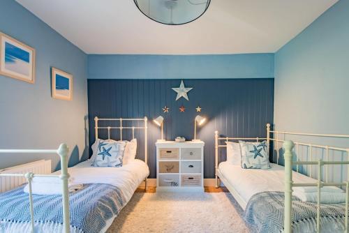 two beds in a bedroom with blue walls at Pebble Beach Cottage by Keepers Cottages in Kingsdown