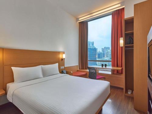 a hotel room with a bed and a large window at Ibis Singapore Novena in Singapore