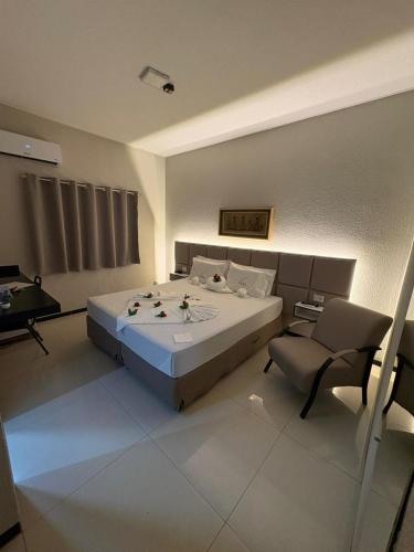 a bedroom with a large bed and a chair at Plumas hotel in Tucuma