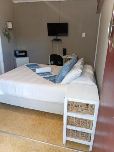a bedroom with a large white bed with a desk at Traquil Stays BnB in Klerksdorp
