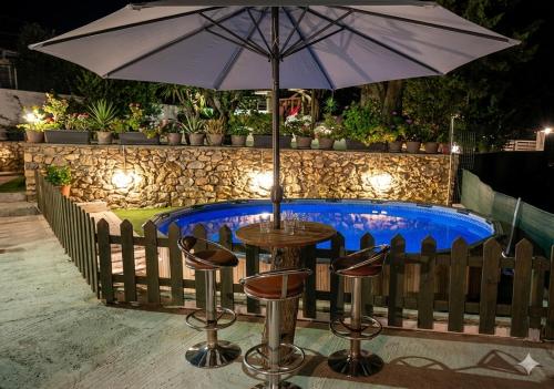 a table with an umbrella next to a swimming pool at Anna's Country Villa Privé in Karés