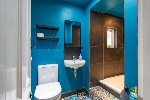 a blue bathroom with a toilet and a sink at Whispering Waves by Keepers Cottages in Hythe