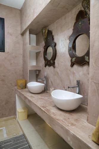 two sinks in a bathroom with two mirrors on the wall at Villa l'olivier in Djerba