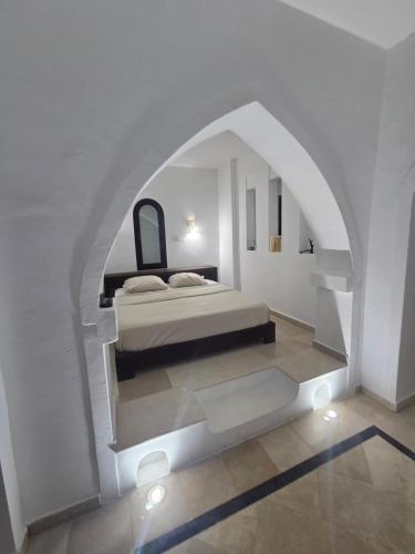 a bedroom with a bed in a white room at Villa l'olivier in Djerba