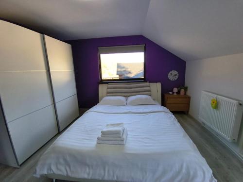 a small bedroom with a white bed with a purple wall at Casa Roxana in Pangarati