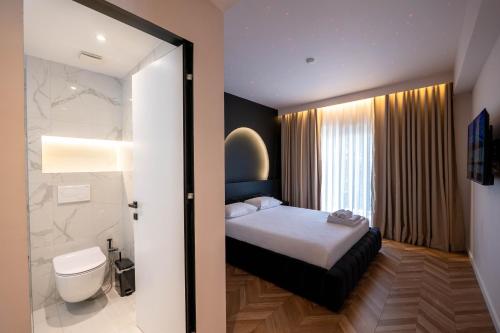 a bedroom with a bed and a bathroom with a toilet at Hotel Almar in Sarandë