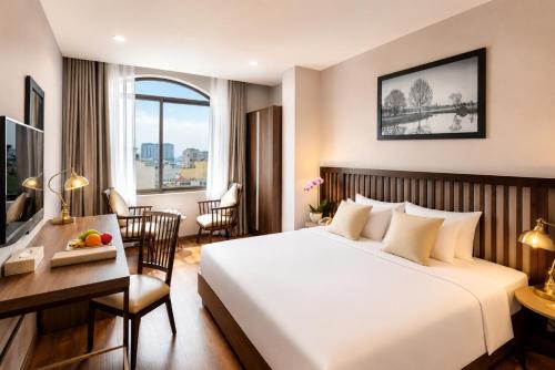 a hotel room with a bed and a desk and a table with a computer at Happy Life Grand Hotel & Rooftop Skybar in Ho Chi Minh City