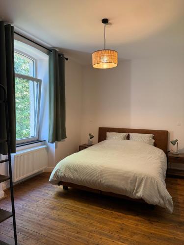 a bedroom with a bed and a large window at Le Clos des Marronniers in Léglise