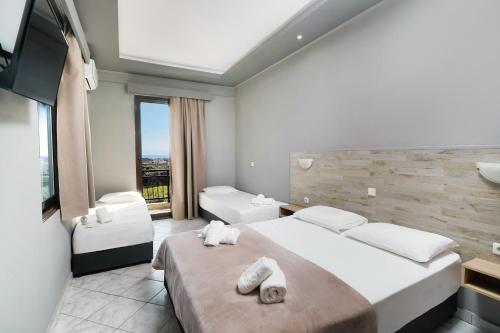 una camera d'albergo con due letti e una grande finestra di Meni Studios a Limenaria