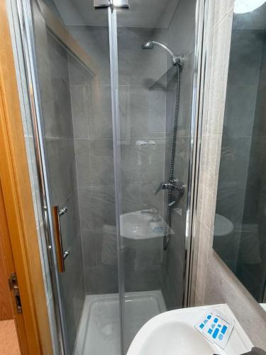 a shower with a glass door next to a toilet at Hotel Ibiza in Sitges