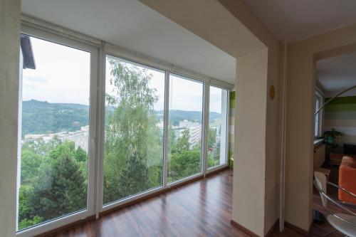 an empty living room with large windows and wood floors at Czech Family Home in Český Krumlov
