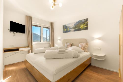 a white bedroom with a bed and a tv at Lake Lodge Ossiacher See in Annenheim
