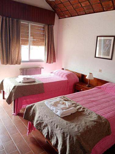 a hotel room with two beds and a window at Hotel El Colonial in San Antonio Oeste