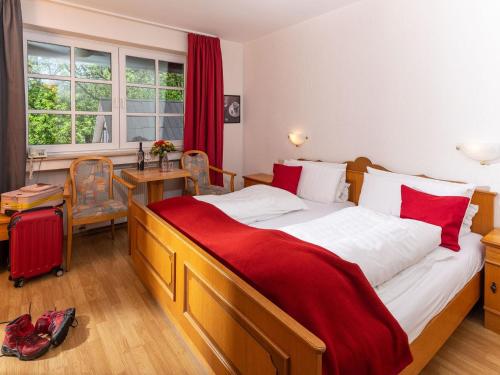 a bedroom with a large bed and a table with a red blanket at Gut Ahe Landgasthof Cafe Event in Kirchhundem