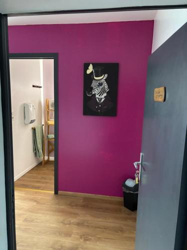 a room with a purple wall with a picture on it at Le Bouthiry in Le Saint