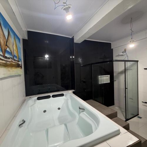 a large white tub in a bathroom with a shower at vista mar suite luxo in Angra dos Reis