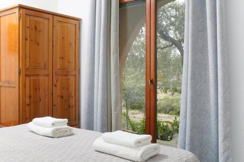 a bedroom with two towels on a bed with a window at Giola Bungalows Sirines in Astris