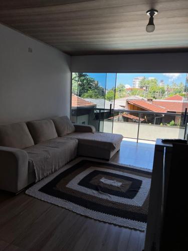 a living room with a couch and a large window at Hospedagem Doce lar in Joinville