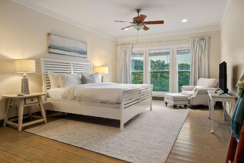 a bedroom with a white bed and a chair and window at Captain's Quarters in Smithville