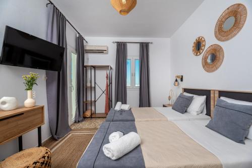 a bedroom with two beds and a flat screen tv at Nikos Hotel in Karterados