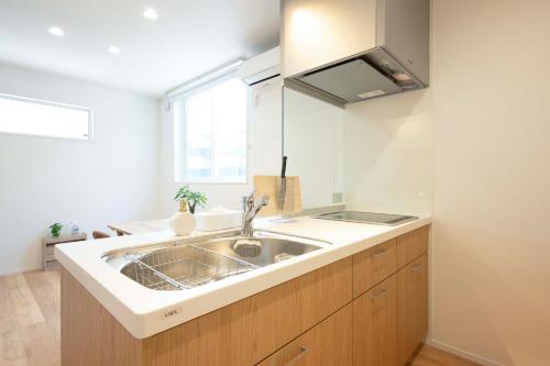 a kitchen with a sink and a window at HIKARIE Modern Stay Toyama in Toyama