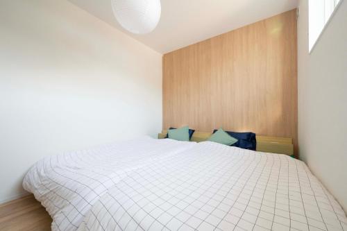 a bedroom with a white bed and a wooden wall at HIKARIE Modern Stay Toyama in Toyama