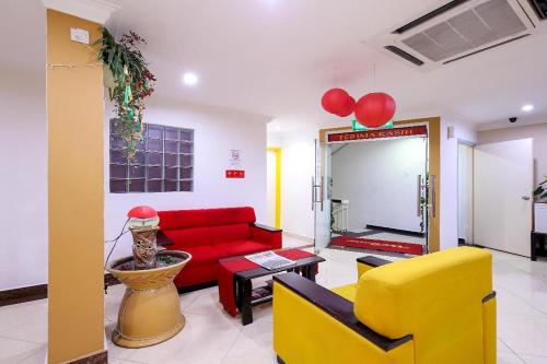 a living room with a red couch and yellow chairs at Puteri Ampang Hotel in Ampang