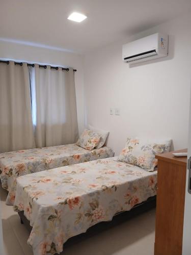 a bedroom with two beds and a air conditioner at Ocean garden in Cabo Frio