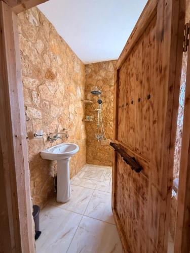 a bathroom with a toilet and a sink and a wooden door at DANA First View Hotel in Dana