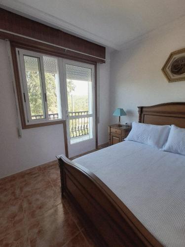 a bedroom with a large bed and two windows at A Morada do Cuco in Piñor