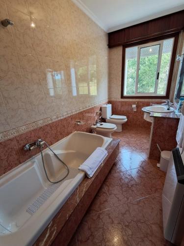 a large bathroom with a tub and two toilets at A Morada do Cuco in Piñor