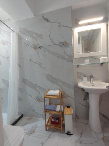 a white bathroom with a sink and a mirror at Manganas Studios in Paleokastritsa