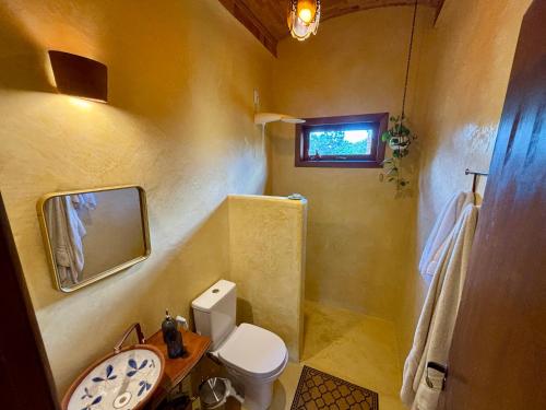 a bathroom with a toilet and a sink and a mirror at Casa Pequi in Alexânia