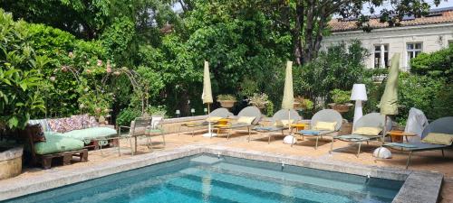 a swimming pool with chairs and tables next to at Villa Aigarden in Avignon