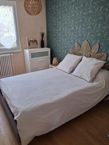 a bedroom with a large bed with white sheets at Le jardin aux iris in Tonnerre