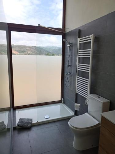 a bathroom with a shower and a toilet and a window at Casa da Fraga in Alfândega da Fé