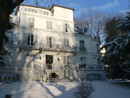 Una gran casa blanca con nieve en el suelo en Chambre Eugénie, en Saint-Cloud