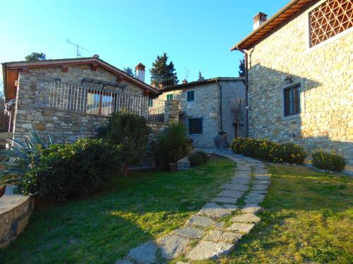 a stone house with a grass yard next to a building at Agriturismo Circugnano in Grassina