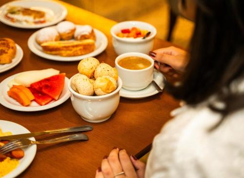 a woman sitting at a table with plates of food at Kastel Manibu Recife - Boa Viagem in Recife