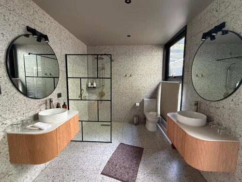 a bathroom with two sinks and a toilet and mirrors at Hotel Patagonia House in Coihaique