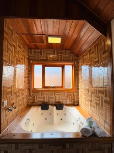 a large bath tub in a room with a window at Chales Vale da Nascente in Monte Verde