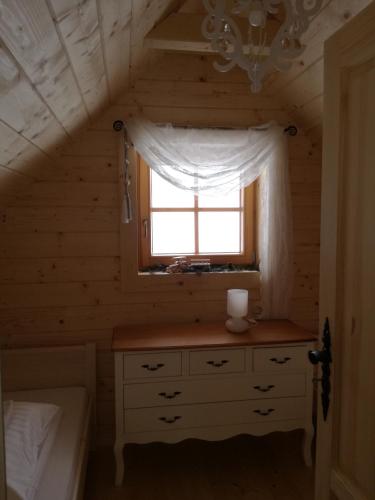 a bedroom with a window and a dresser in a log cabin at Całoroczne domki Pasja II View,Lake & Ski in Kluszkowce