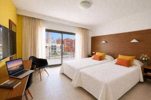 a hotel room with two beds and a laptop on a desk at Prince Park in Benidorm