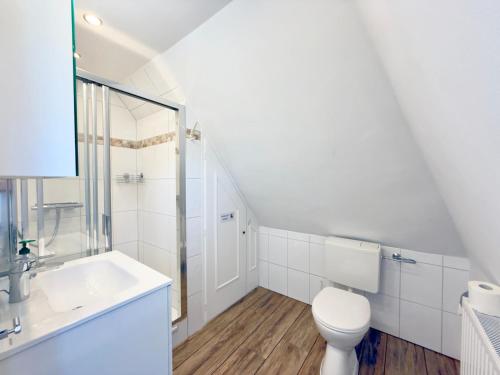 a white bathroom with a toilet and a sink at Westerheide 51, App 1 in Wenningstedt